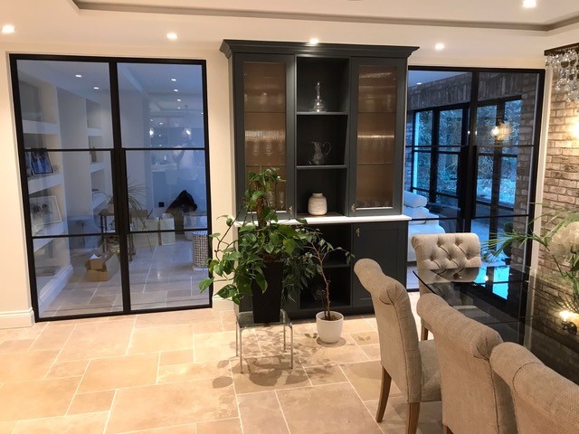 Discover where fire rated steel doors are commonly used 2 A dining room featuring two sets of black-framed steel glass doors flanking a dark grey built-in cabinet.